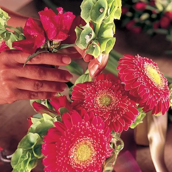 Mains de fleuriste préparant un bouquet de fleurs fraîches